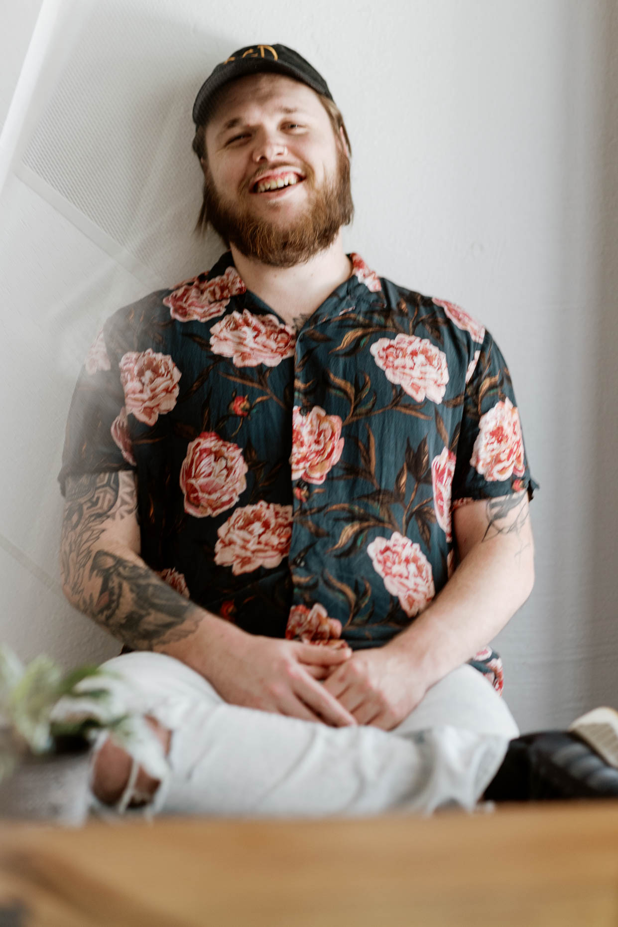Relaxed and fun portrait of a young hipster guy wearing a cap and floral pattern shirt