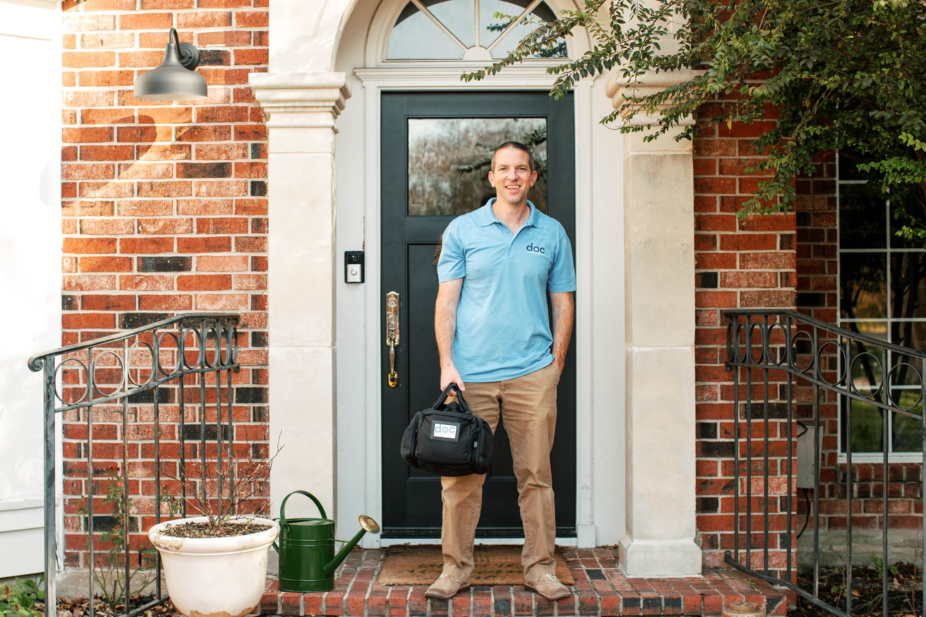 portrait of male healthcare provider standing in front of a home