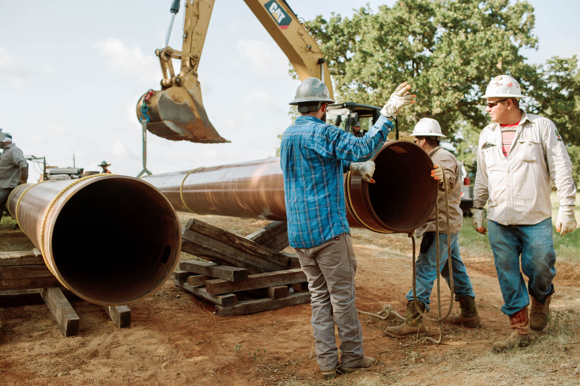 Construction pipeline workers wearing hard hats on job site for a oil and gas pipeline company