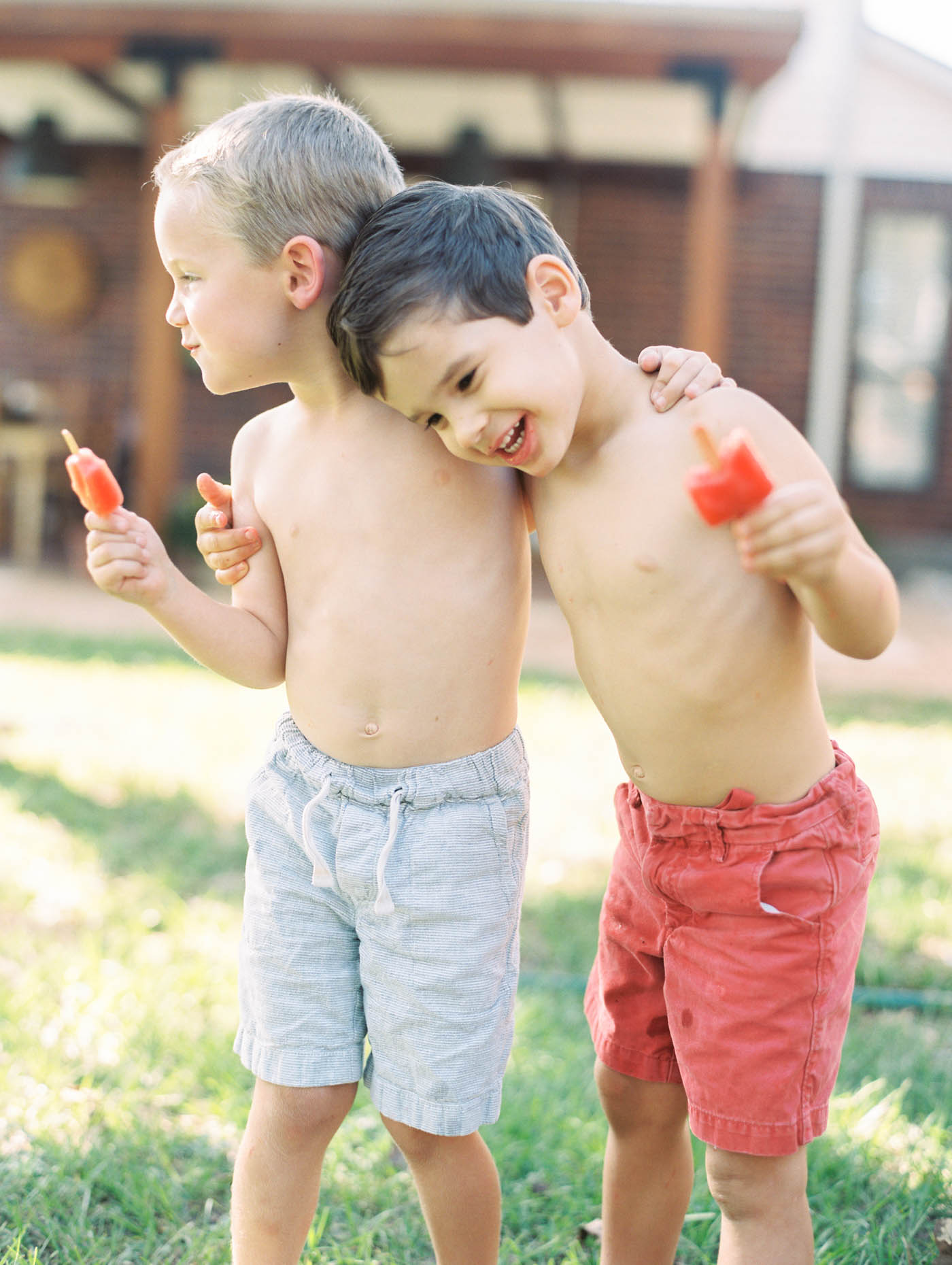 Two young boys eating organic popsicles in a backyard summertime setting 