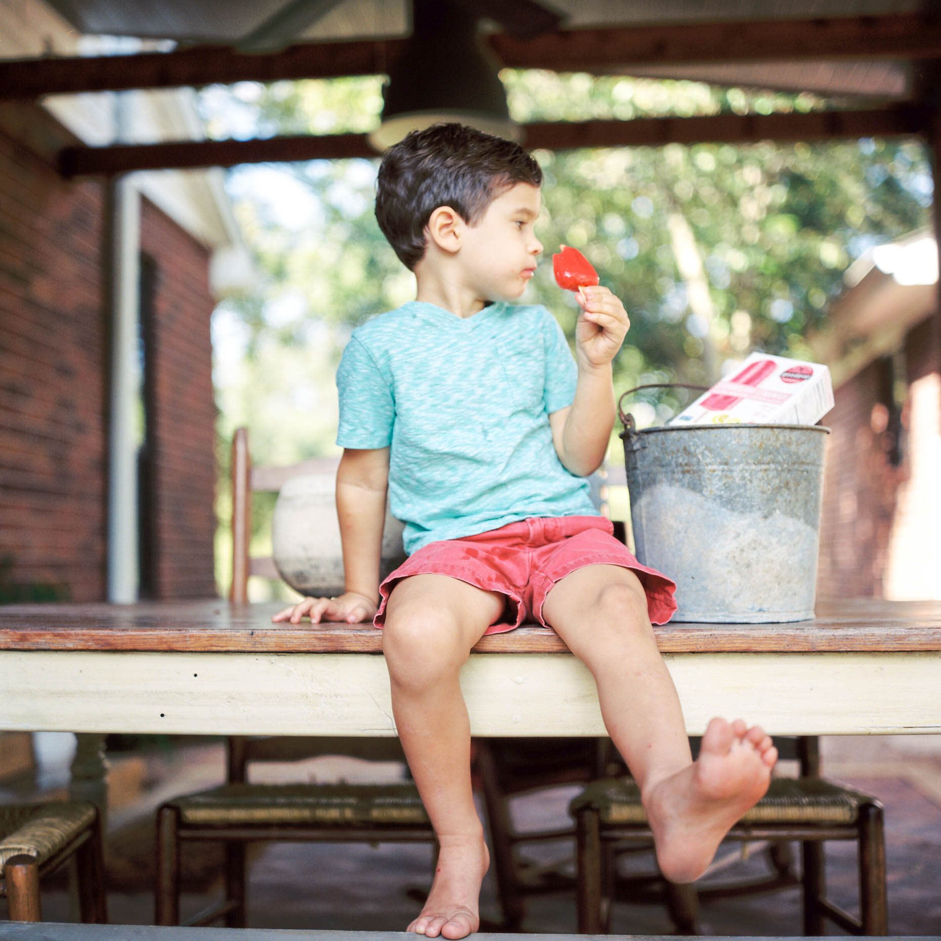 young boy eating an organic popsicle on back porch