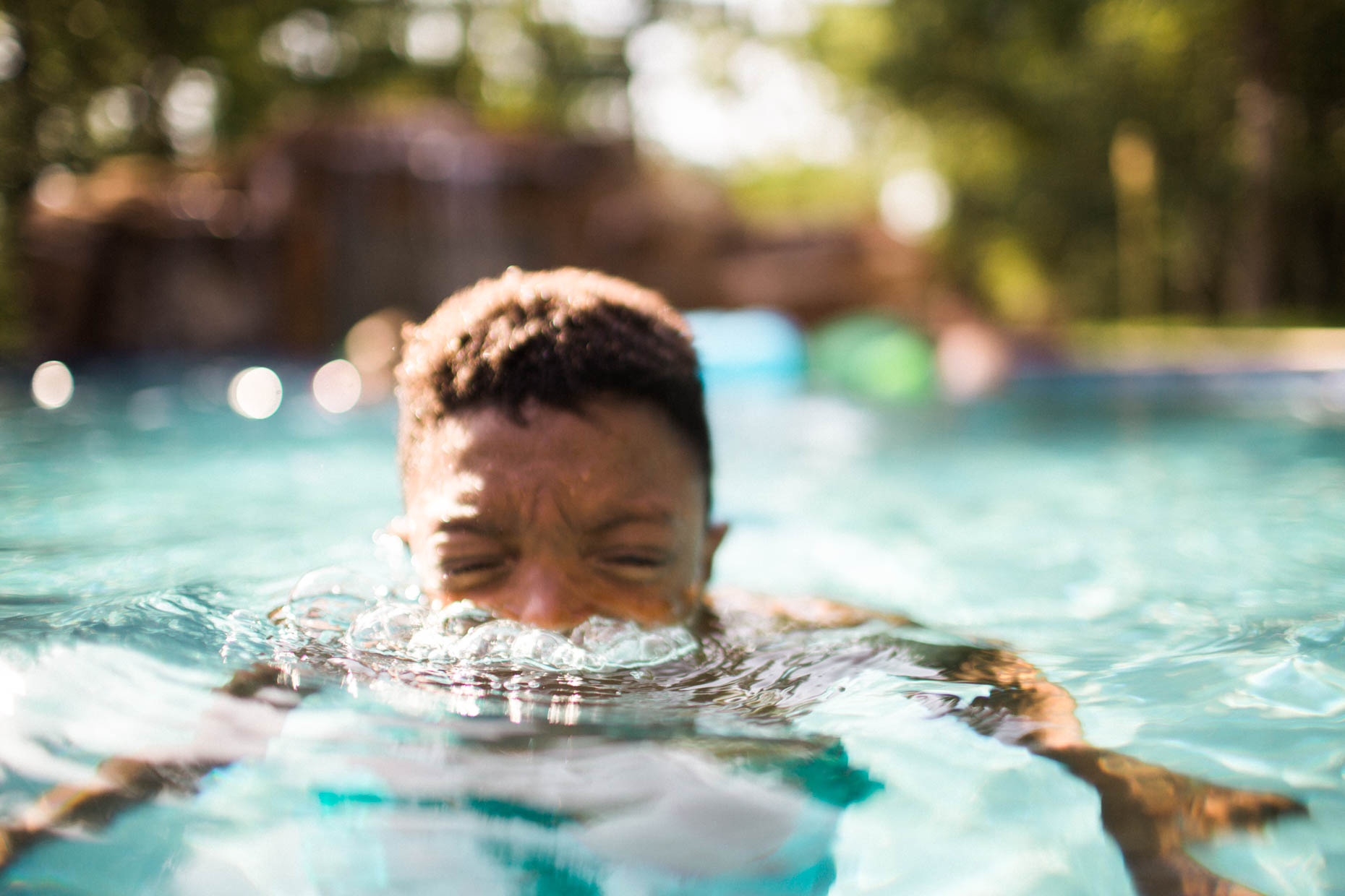 Young black boy submerged in a swimming pool blowing bubbles out of mouth