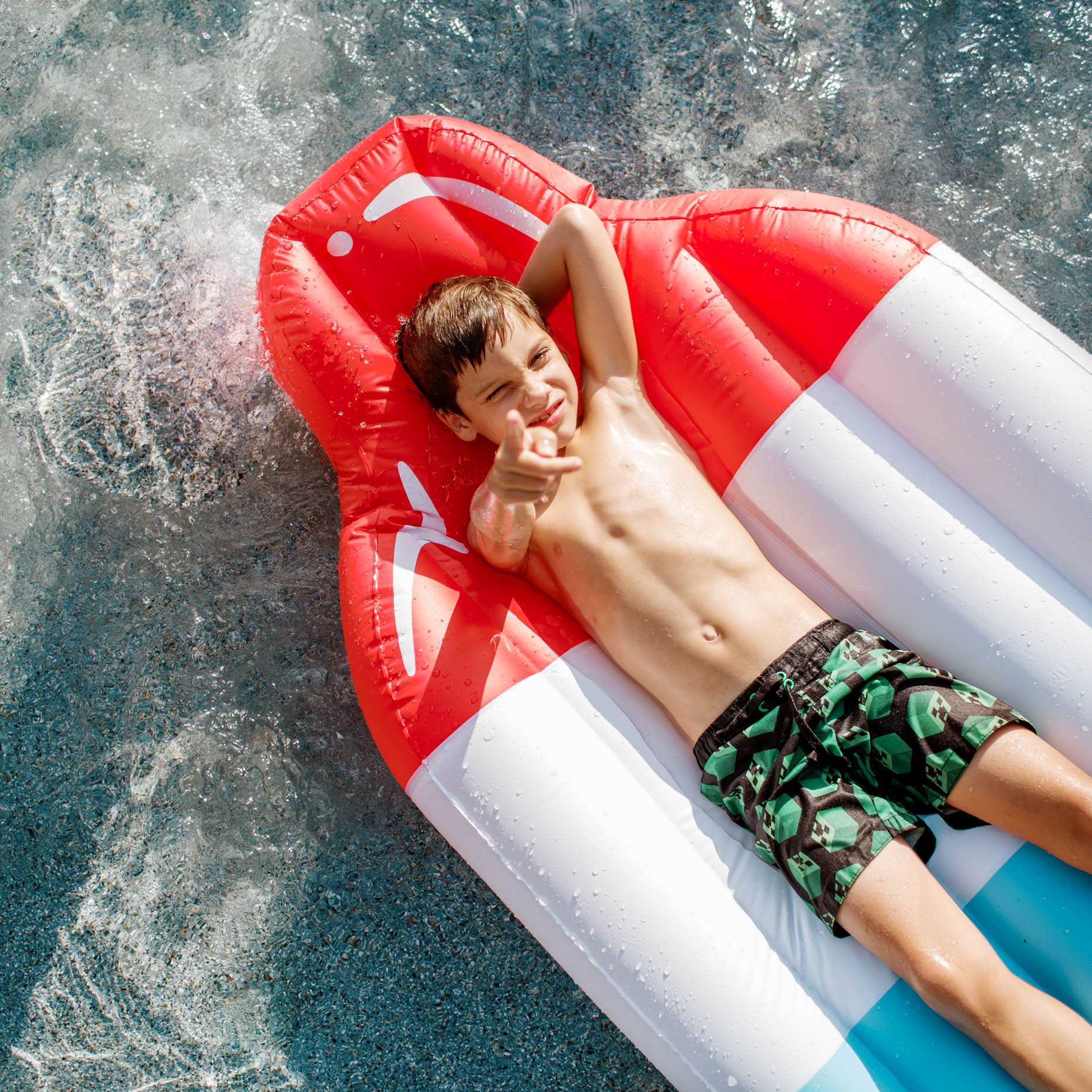 overhead photo of a boy laying on a pool float