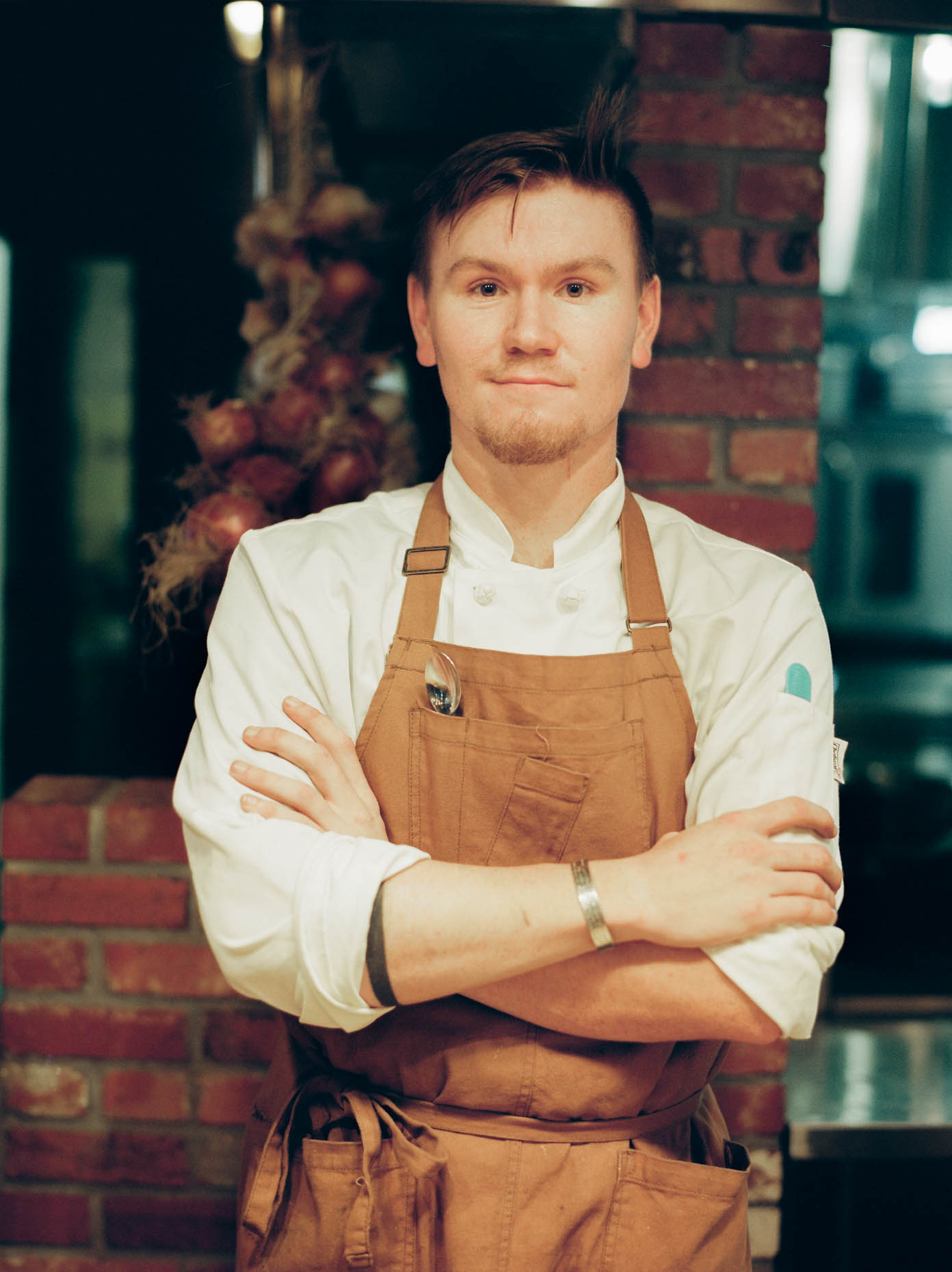Portrait of a male chef standing with crossed arms in a kitchen