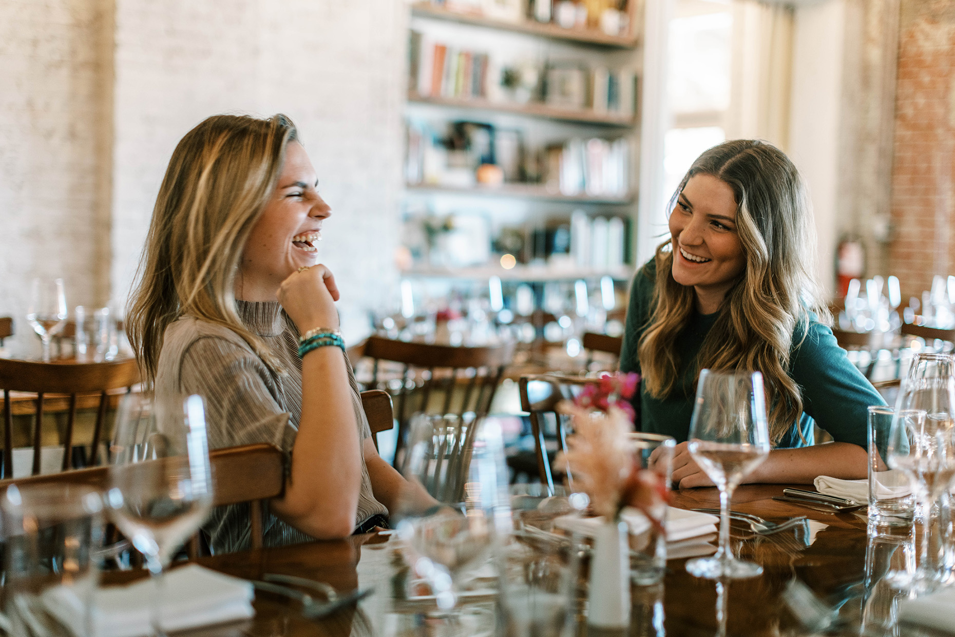 young women laughing and enjoying drinks in a restaurant
