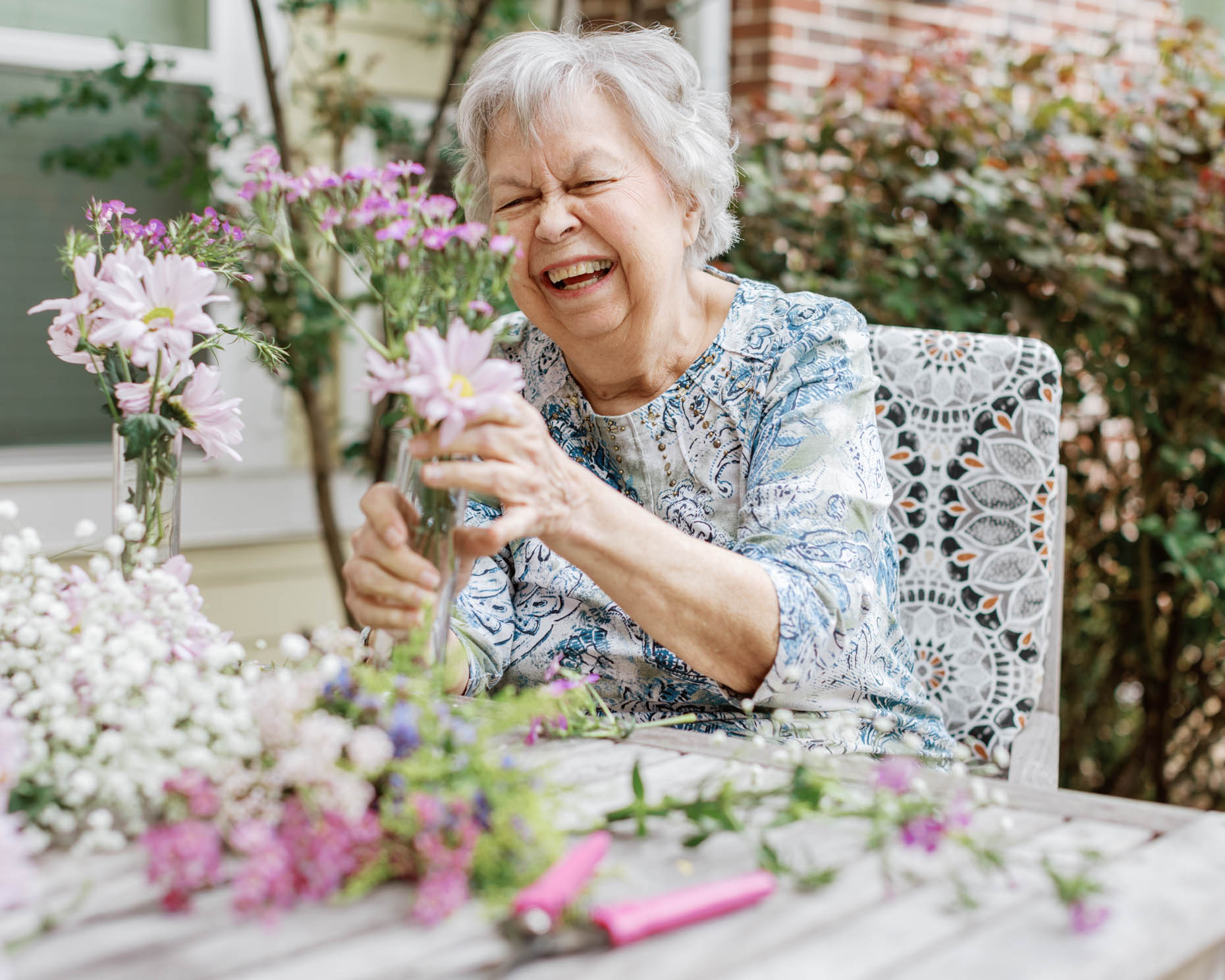 Retired woman arranging flowers happily at a senior living community