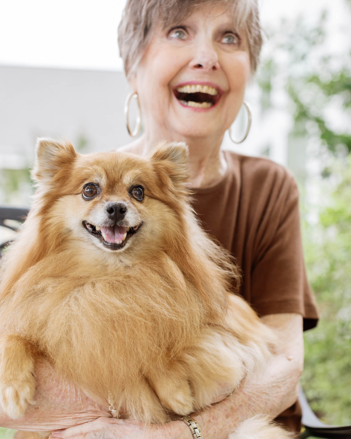 Spunky fun retired woman holding her dog at a senior living community