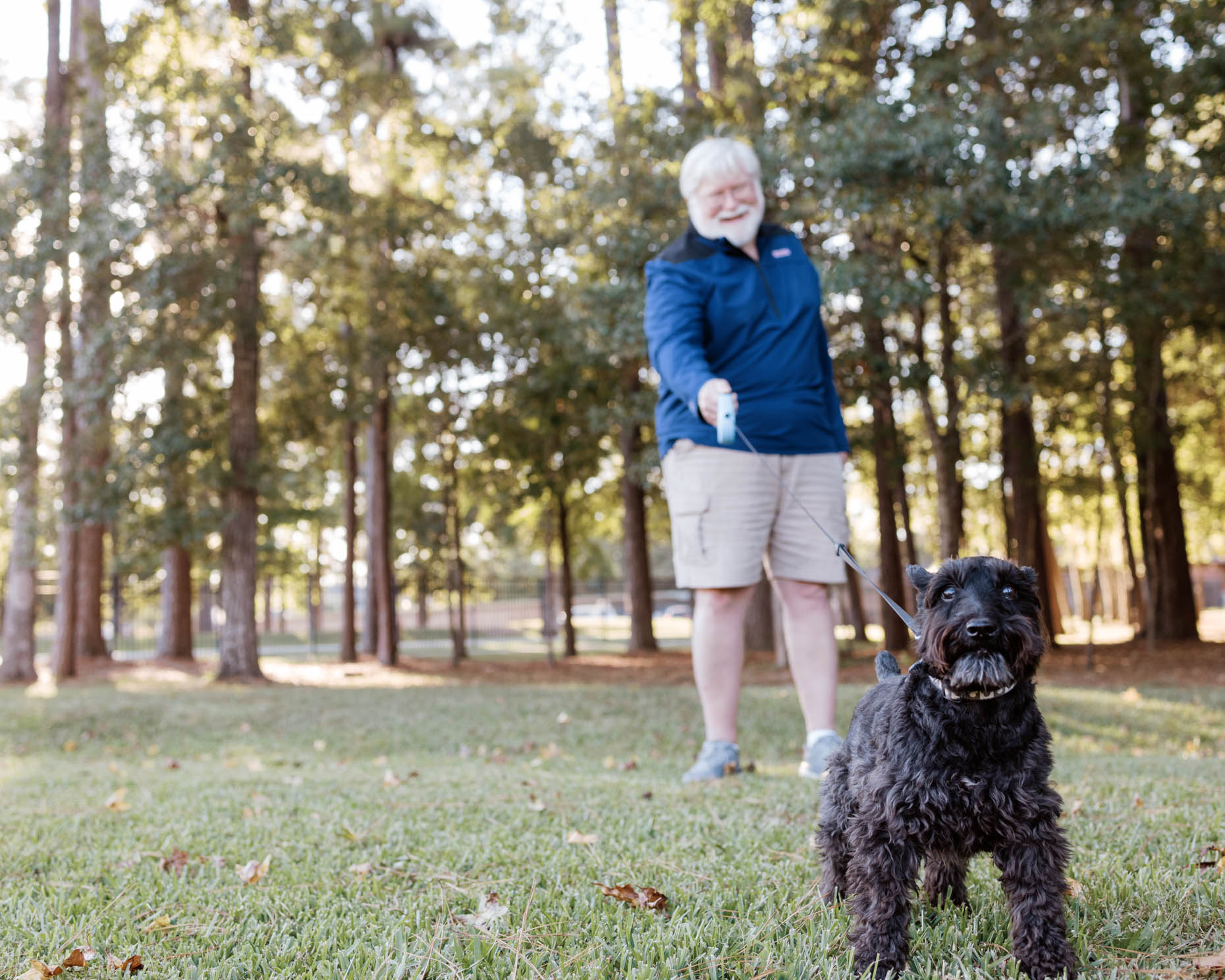 Retired man walking his dog outdoors at a senior living community