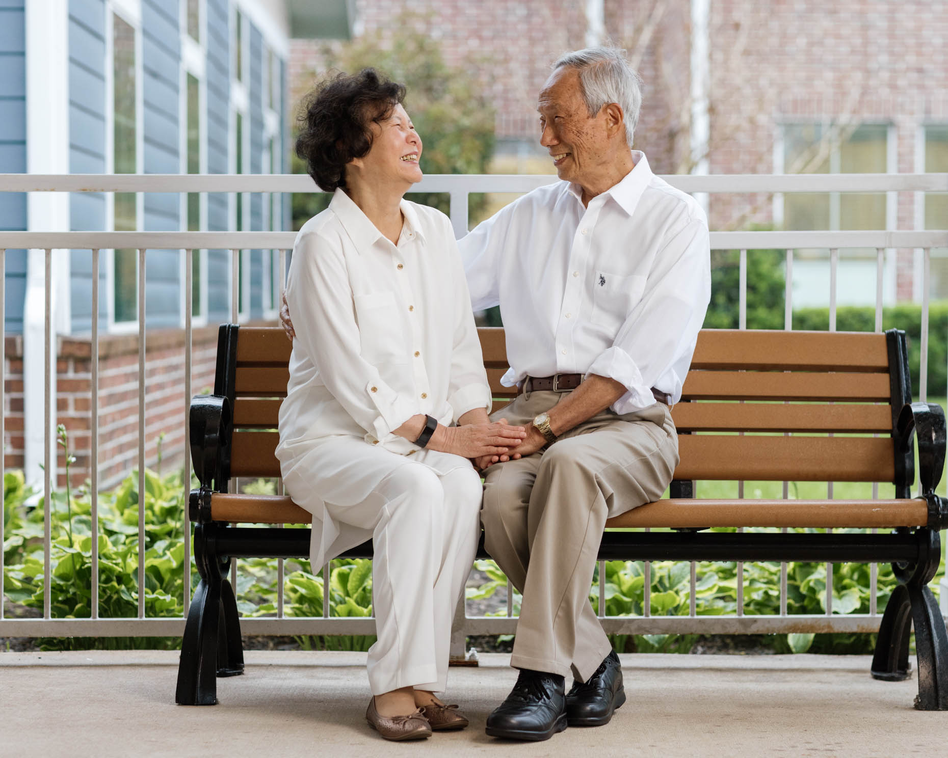 Retired asian couple sitting on a bench at a senior living community