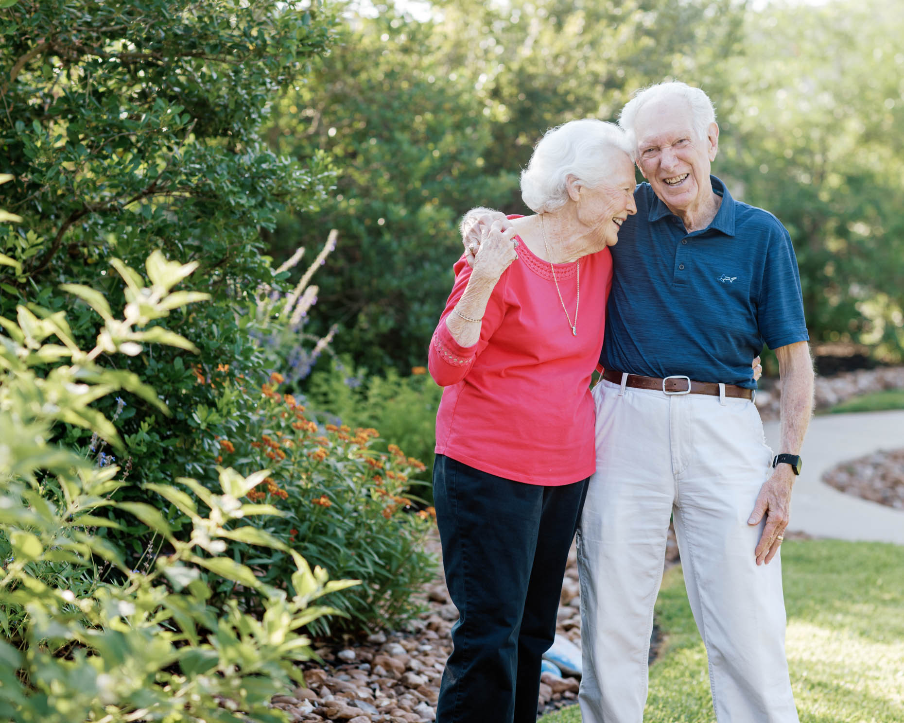 Retired couple casually hugging outdoors at a senior living community