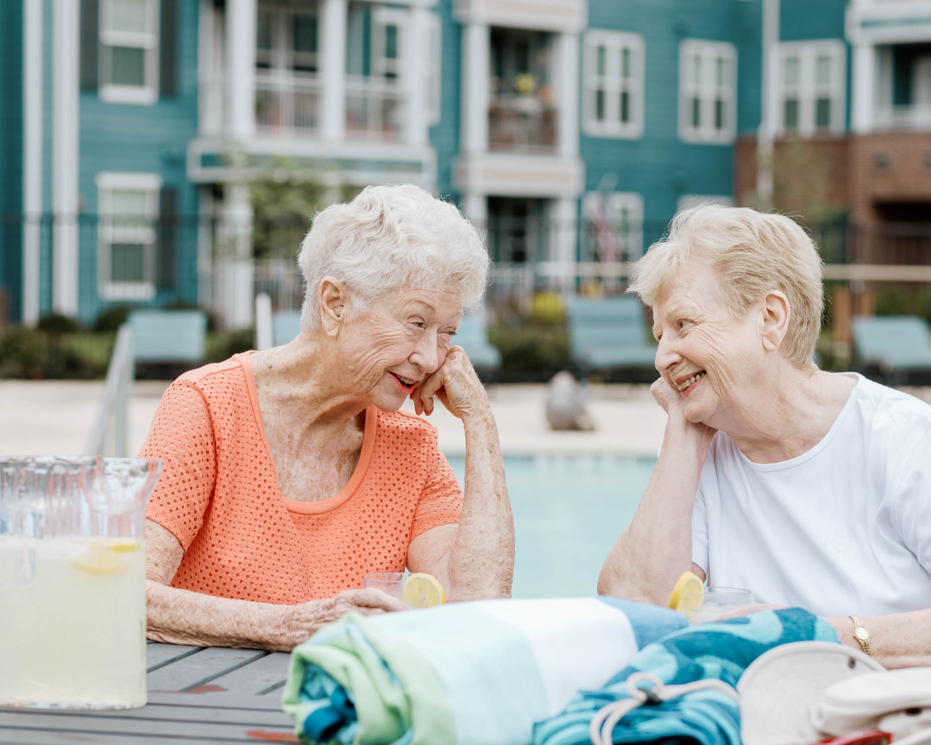Two retired women talking poolside at a senior living community