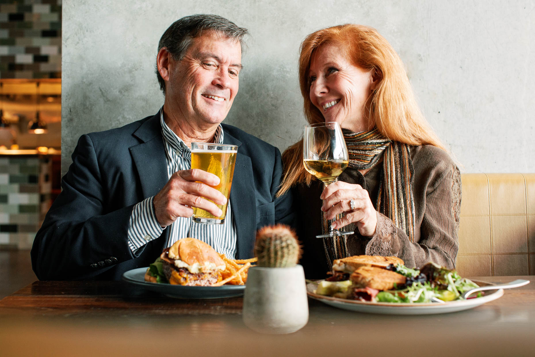 Mid life couple on a date in an up scale restaurant holding beverages and smiling at one another