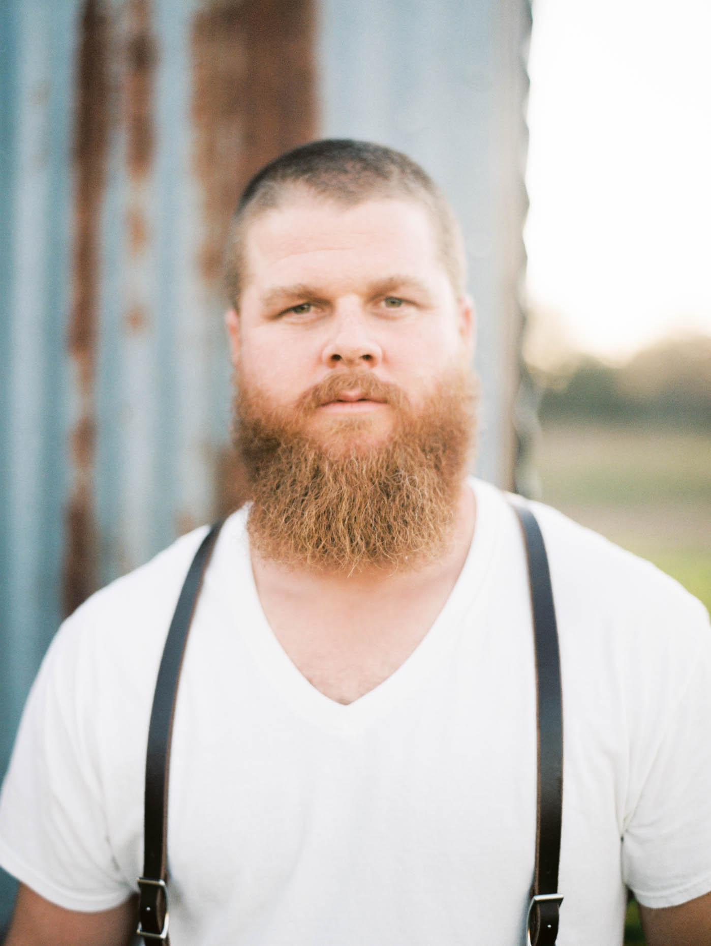 Portrait of an organic Texas farmer wearing a white v-neck shirt and thin black suspenders